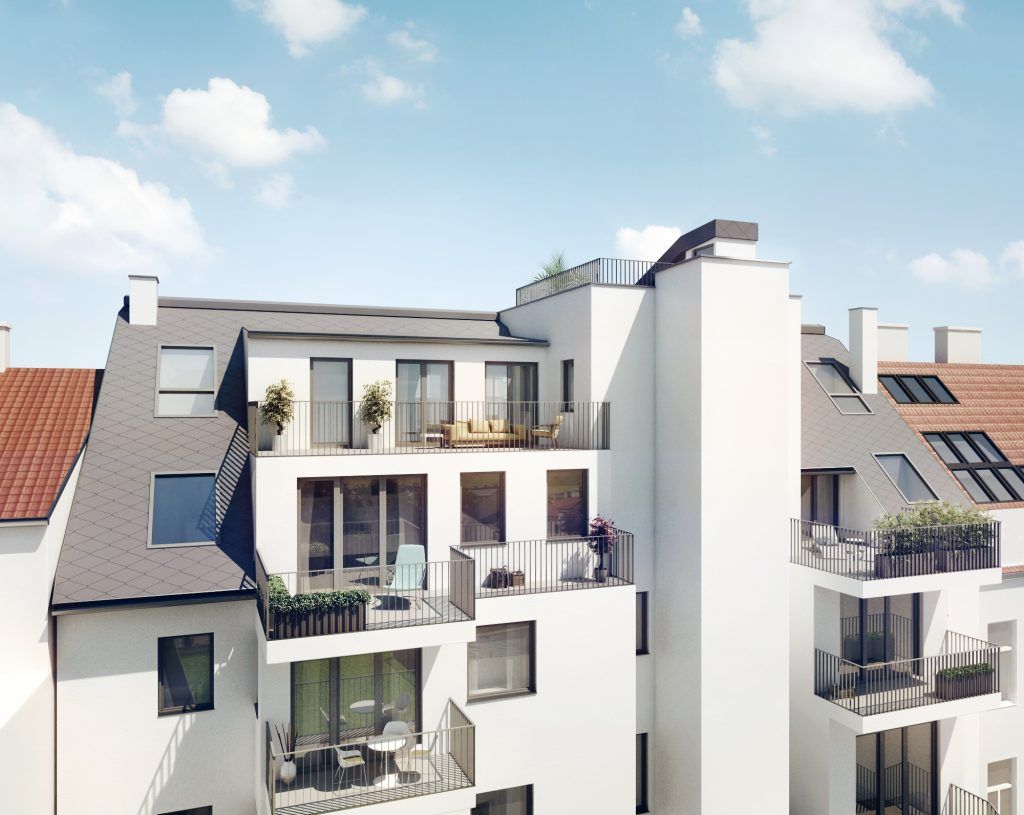 Außenansicht der fertigen, weiß verputzten Rückfassade des Mehrfamilienhauses mit gestuften Balkonen.